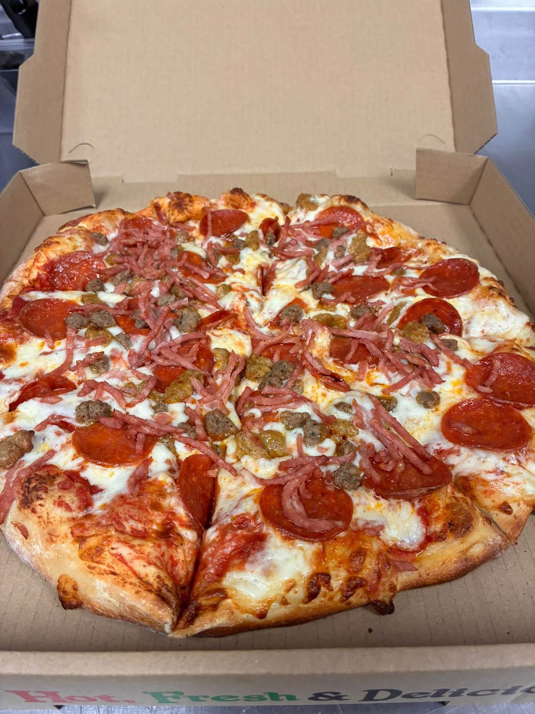 A meat pizza with pepperoni, sausage and ham fresh out of the oven