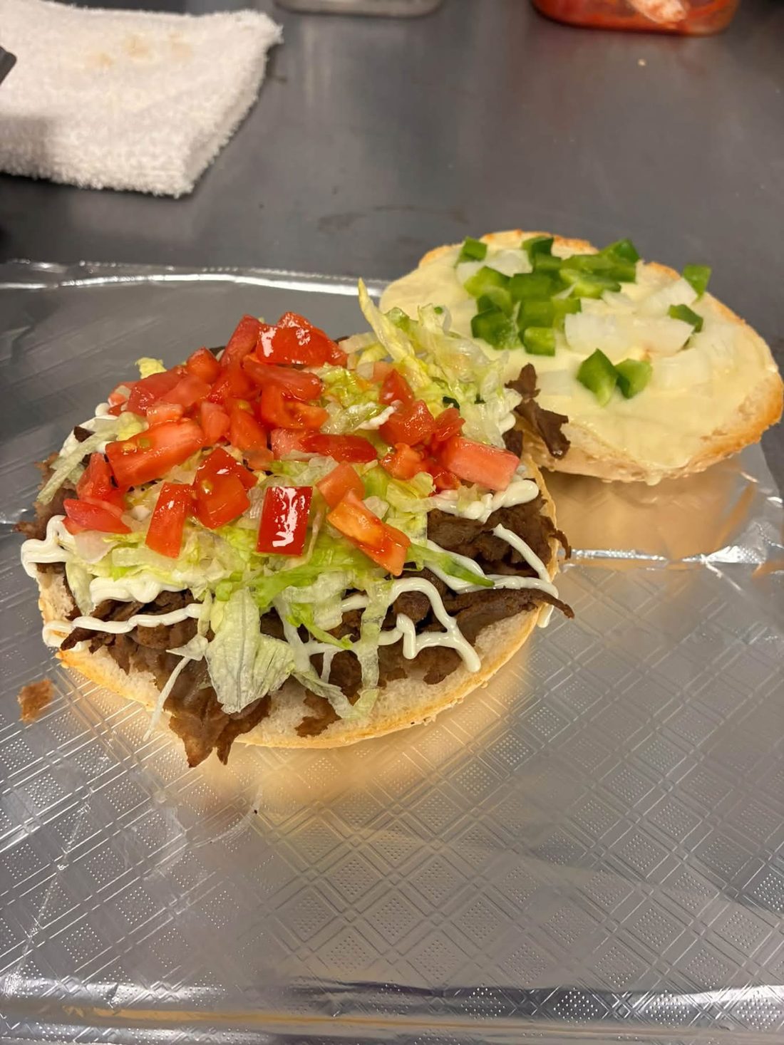 A Steak Muffulatta with lettuce, tomato, peppers and onions