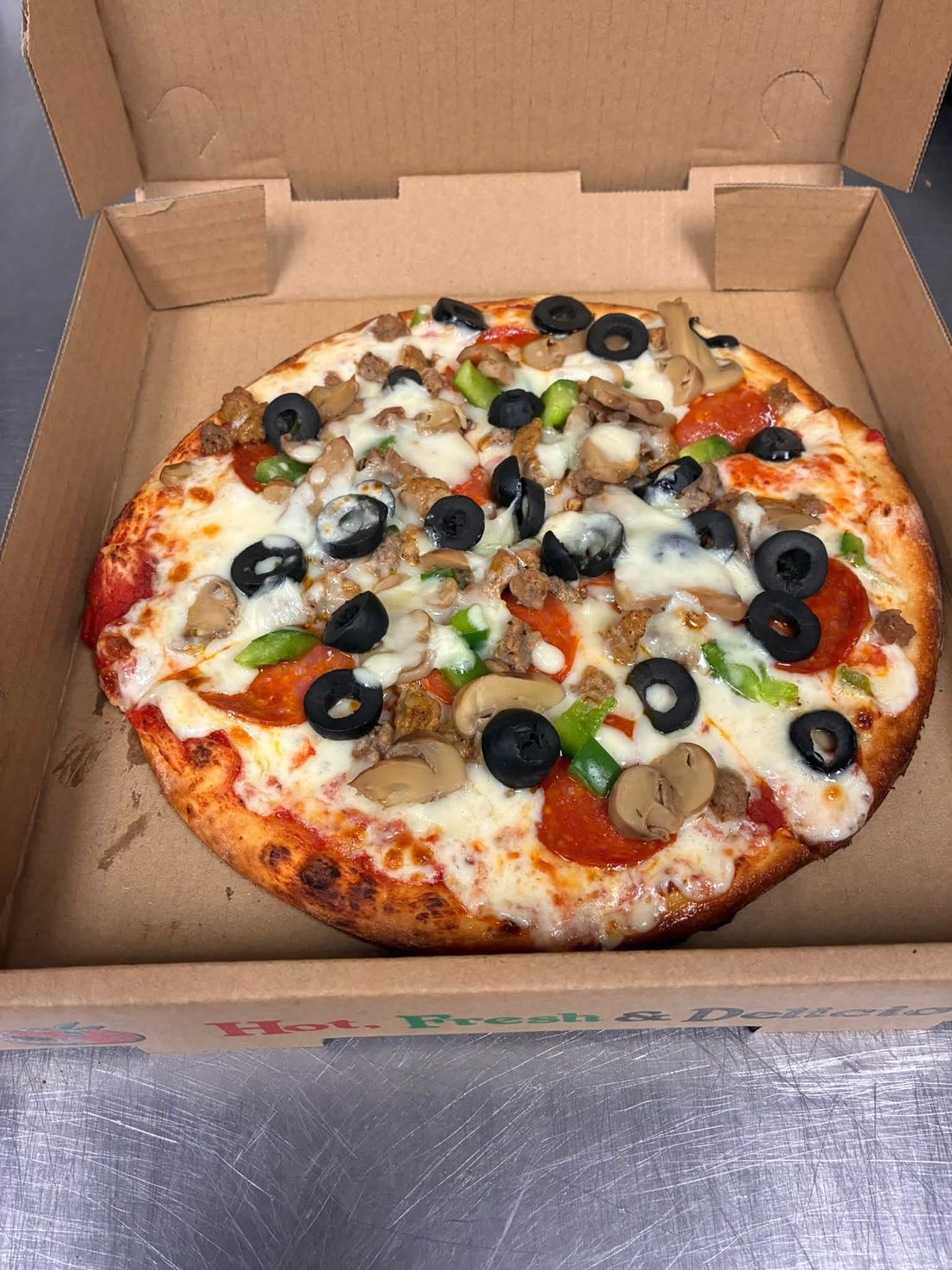 Pizza with pepperoni, sausage, mushrooms, peppers and black olives