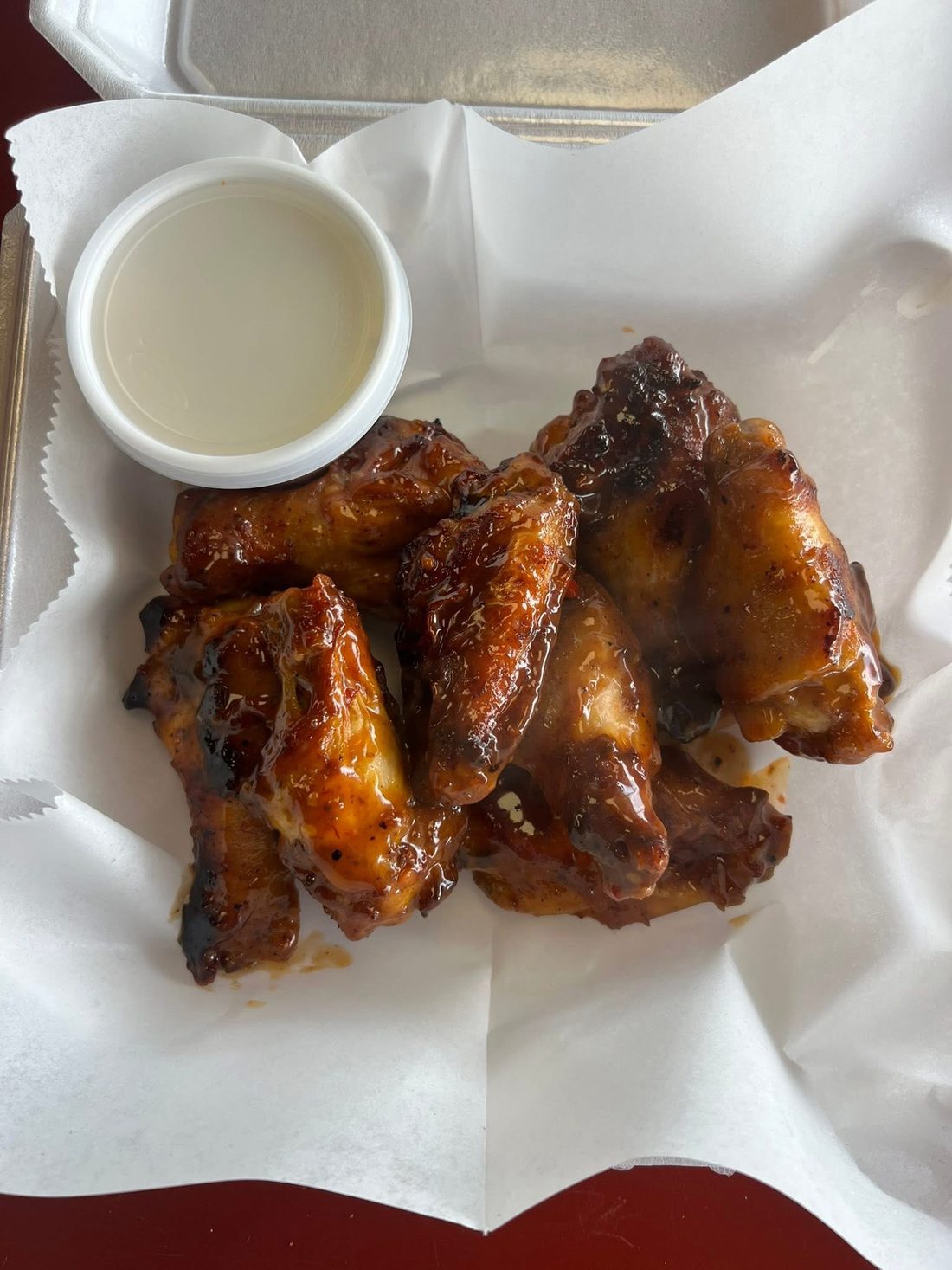 Glazed wings with a cup of dipping sauce